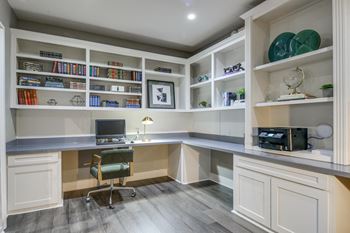 a home office with white cabinets and a desk with a computer